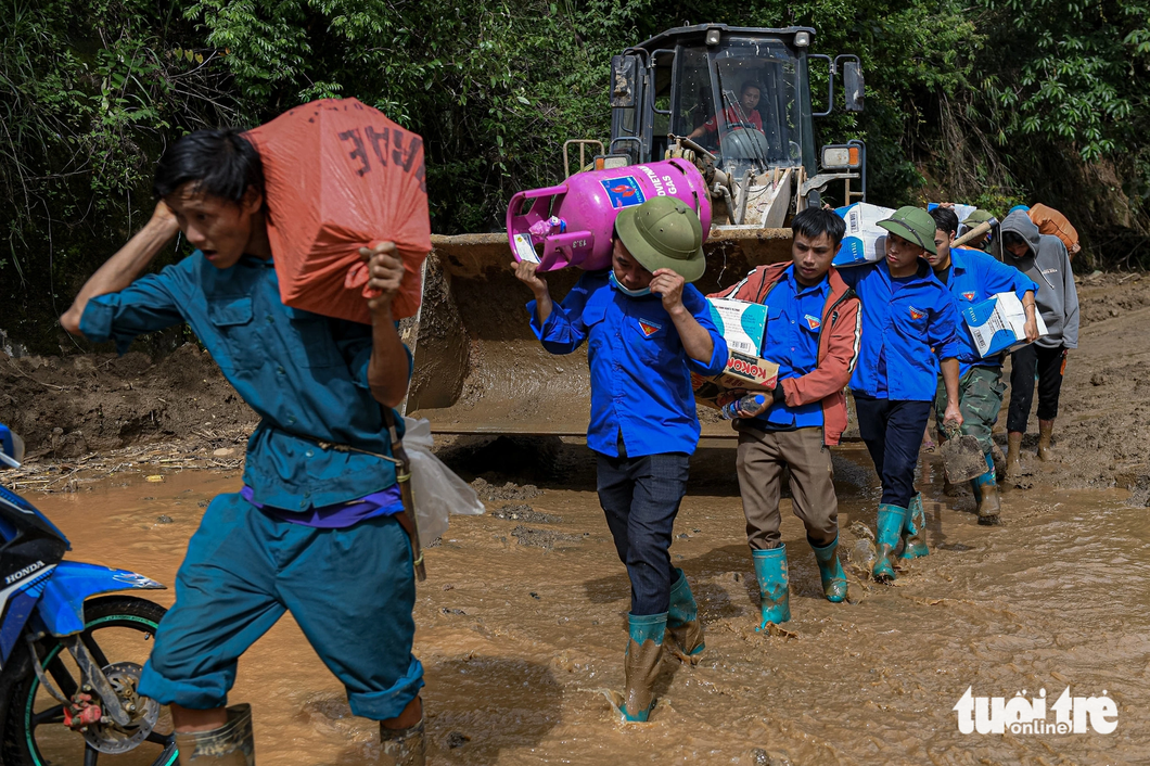 Young men carrying rice, water... with spades and shovels to the flood center - Photo: NAM TRAN