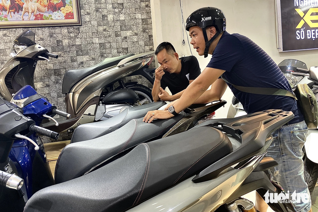 A customer who came to see the motorcycle with the beautiful license plate expressed concern about the procedures to transfer the name of the old car - Photo: TIEN QUOC