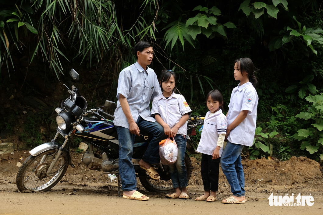 Anh Thào A Lồng (34 tuổi) đèo ba con gái là Thào Thị Của, Thào Thị Dùa và Thào Thị Dở vượt 15km đường núi từ bản Háng Á xa xôi đến tựu trường sớm - Ảnh: NGUYÊN BẢO