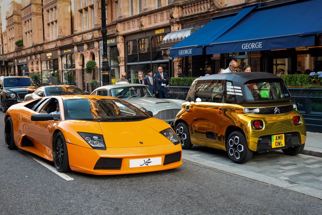 Mini electric car painted so brightly it looks like it's covered in gold, standing next to a supercar Mini electric car painted so brightly it looks like it's covered in gold, standing next to a supercar