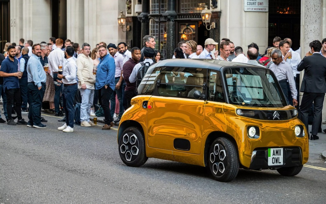 Electric mini car painted so brightly it looks like it's covered in gold, standing next to a supercar Electric mini car painted so brightly it looks like it's covered in gold, standing next to a supercar