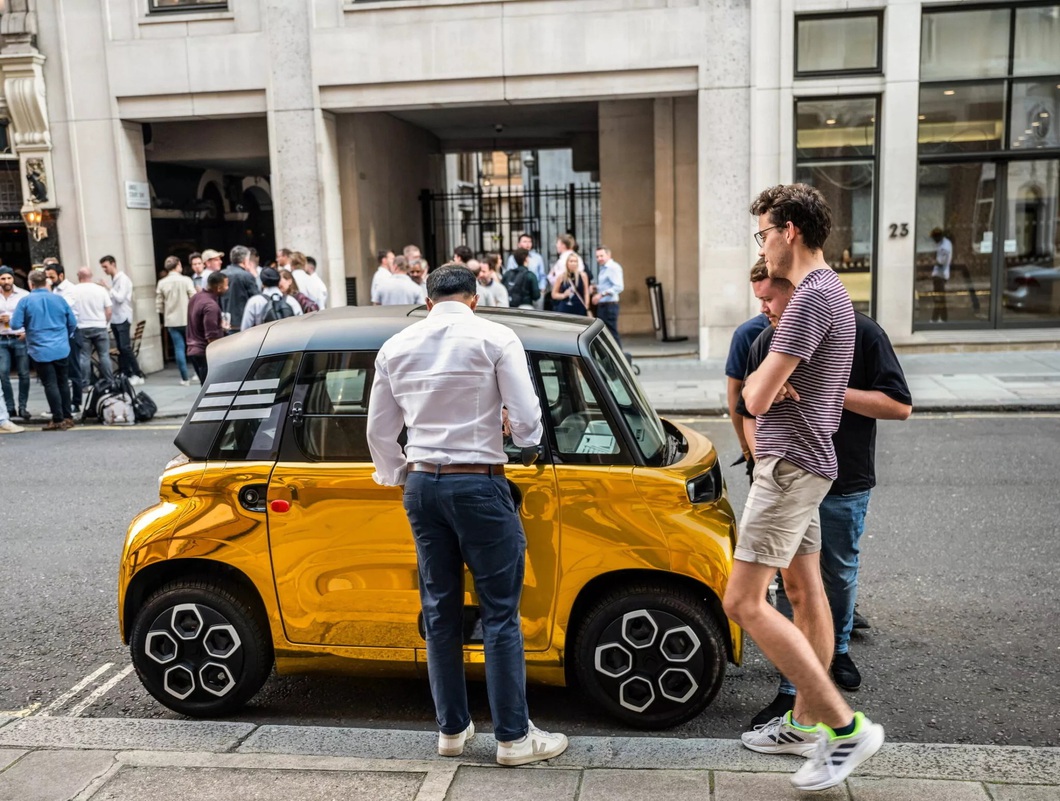 Electric mini car painted so brightly it looks like it's covered in gold, standing next to a supercar Electric mini car painted so brightly it looks like it's covered in gold, standing next to a supercar