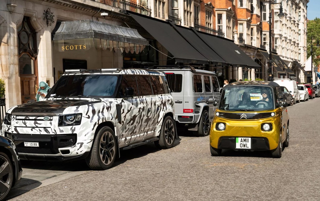 Electric mini car brightly painted as if covered in gold, parked next to supercar Electric mini car brightly painted as if covered in gold, parked next to supercar