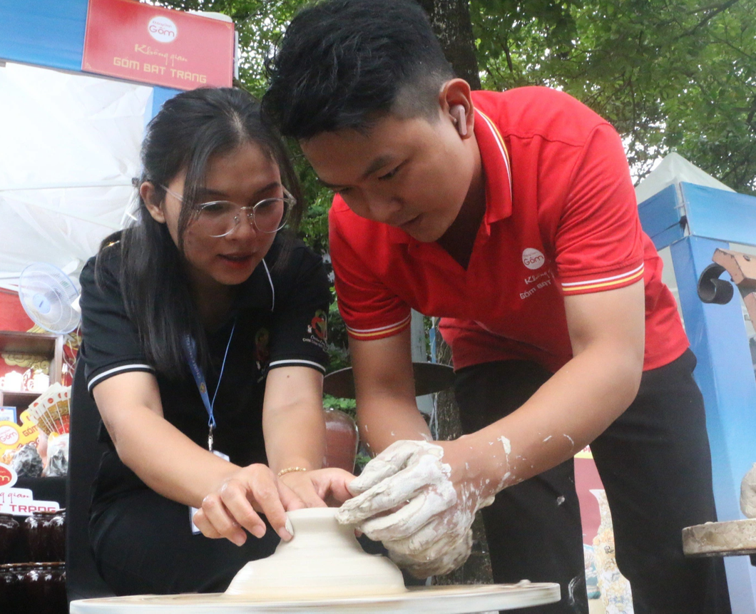 Đoàn Thị Trúc Phương (trái) trải nghiệm làm gốm tại gian hàng gốm Bát Tràng - Ảnh: THÁI THÁI