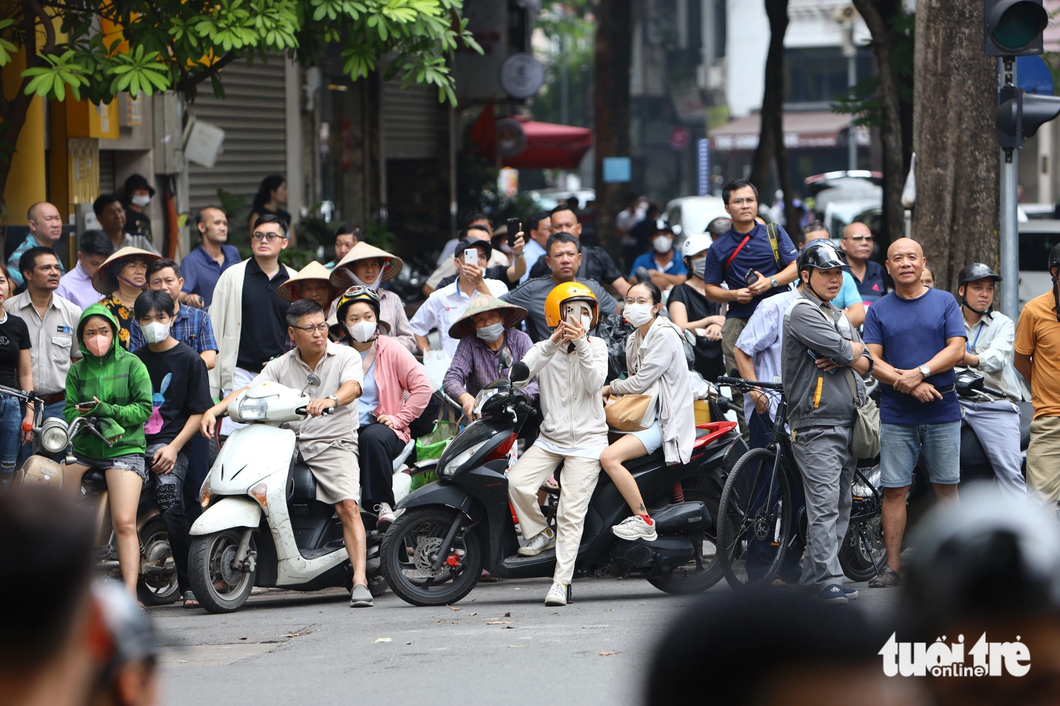 Người dân Hà Nội theo dõi đoàn xe của tổng thống Mỹ di chuyển trên đường ngày 11-9 - Ảnh: DANH KHANG