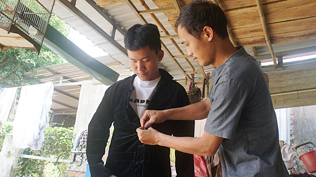 Mr. Li Van Nha, head of Giang Chau village, gave Sung A Giang a traditional shirt of the Mong people to congratulate him on his graduation from university.