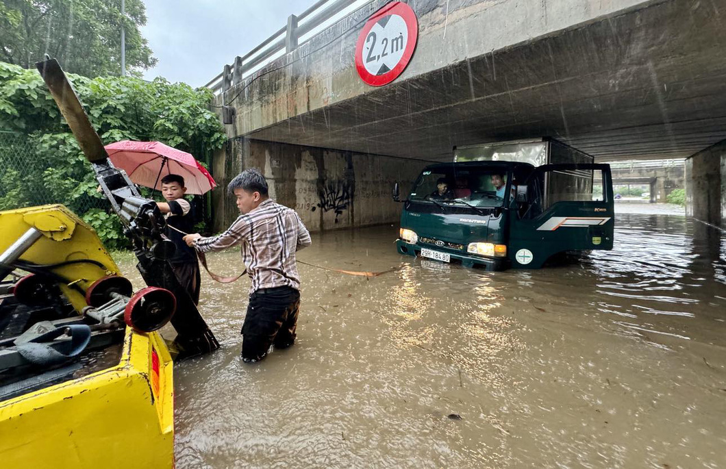 Đường phố Hà Nội ngập sâu vì mưa to, trời tối mịt như ban đêm - Ảnh 7.