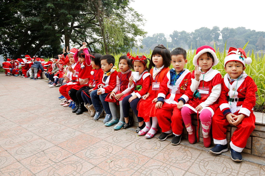 Trẻ em mặc quần áo ông già Noel bên bờ hồ Hoàn Kiếm (Hà Nội).  Ảnh: Reuters/Kham.