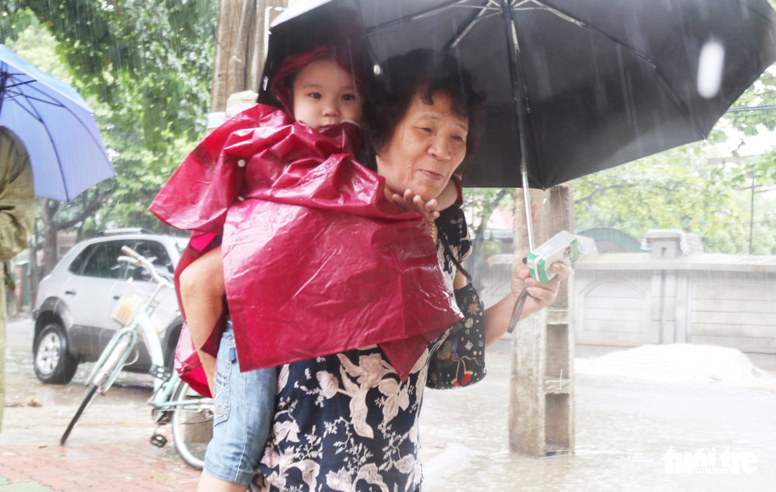 TP Vinh mưa xối xả ngập đường, phụ huynh vất vả đưa con đến trường - Ảnh 2.