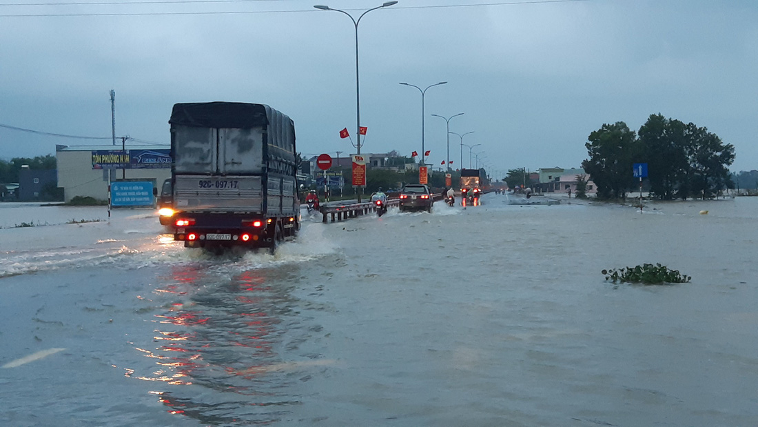 Nước lũ tràn qua quốc lộ 1 vào nhà dân, công an đội mưa điều tiết giao thông - Ảnh 2.