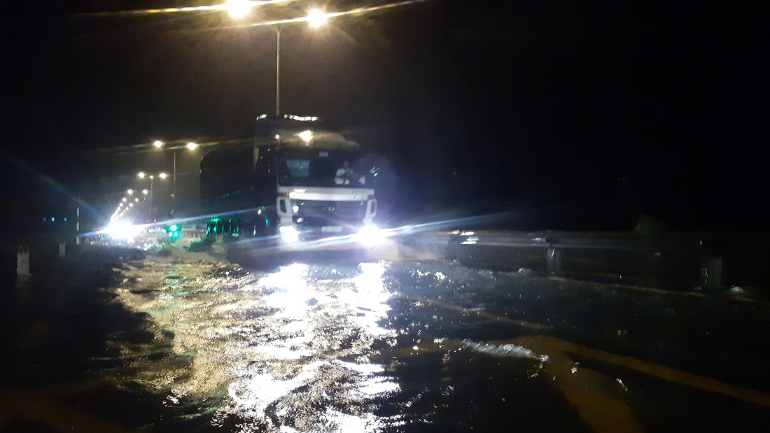 Nước lũ tràn qua quốc lộ 1 vào nhà dân, công an đội mưa điều tiết giao thông - Ảnh 3.