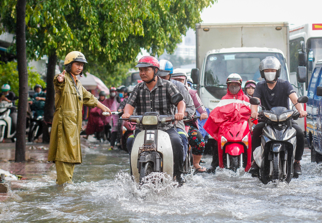 Đường Phạm Văn Đồng ngập, kẹt xe sau mưa lớn, CSGT phải moi rác cho nước chảy - Ảnh 3.