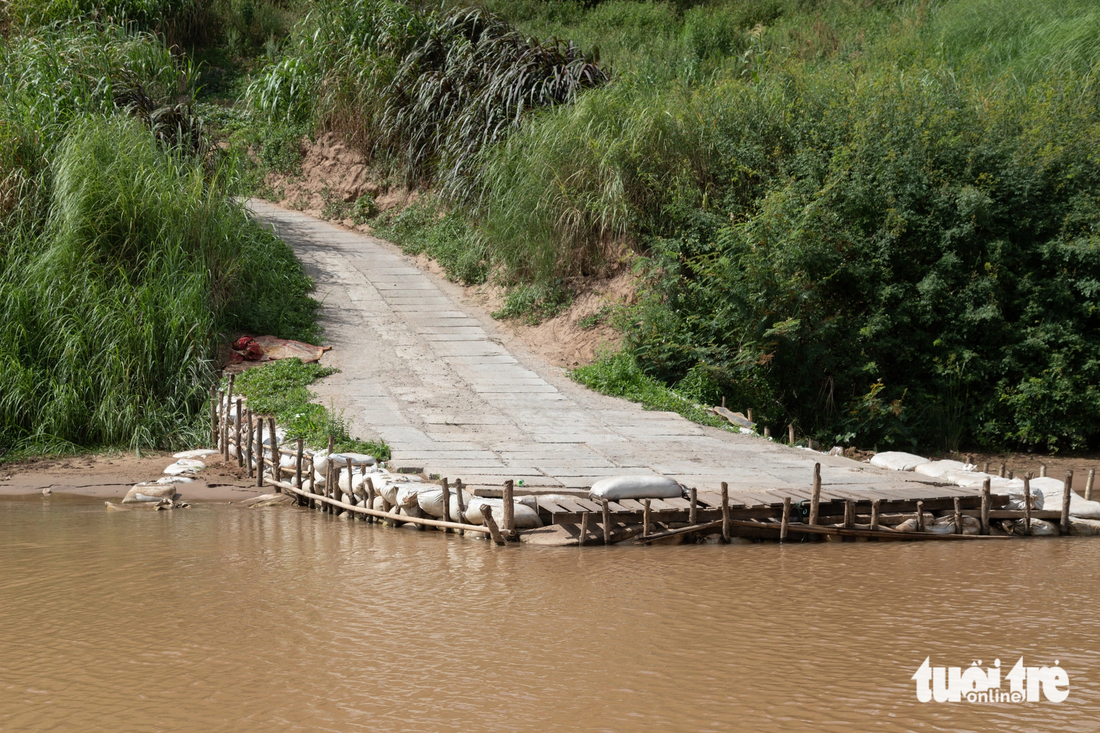 Một đoạn đường bê tông dẫn xuống sông Sê Pôn được người dân tự xây dựng kè chống sạt lở đơn sơ - Ảnh: HOÀNG TÁO