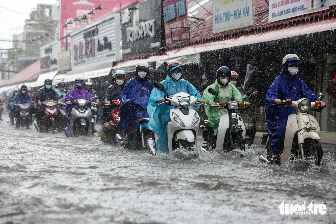 Người dân chật vật di chuyển trên đường Kha Vạn Cân (TP Thủ Đức) trong cơn mưa trưa 10-10