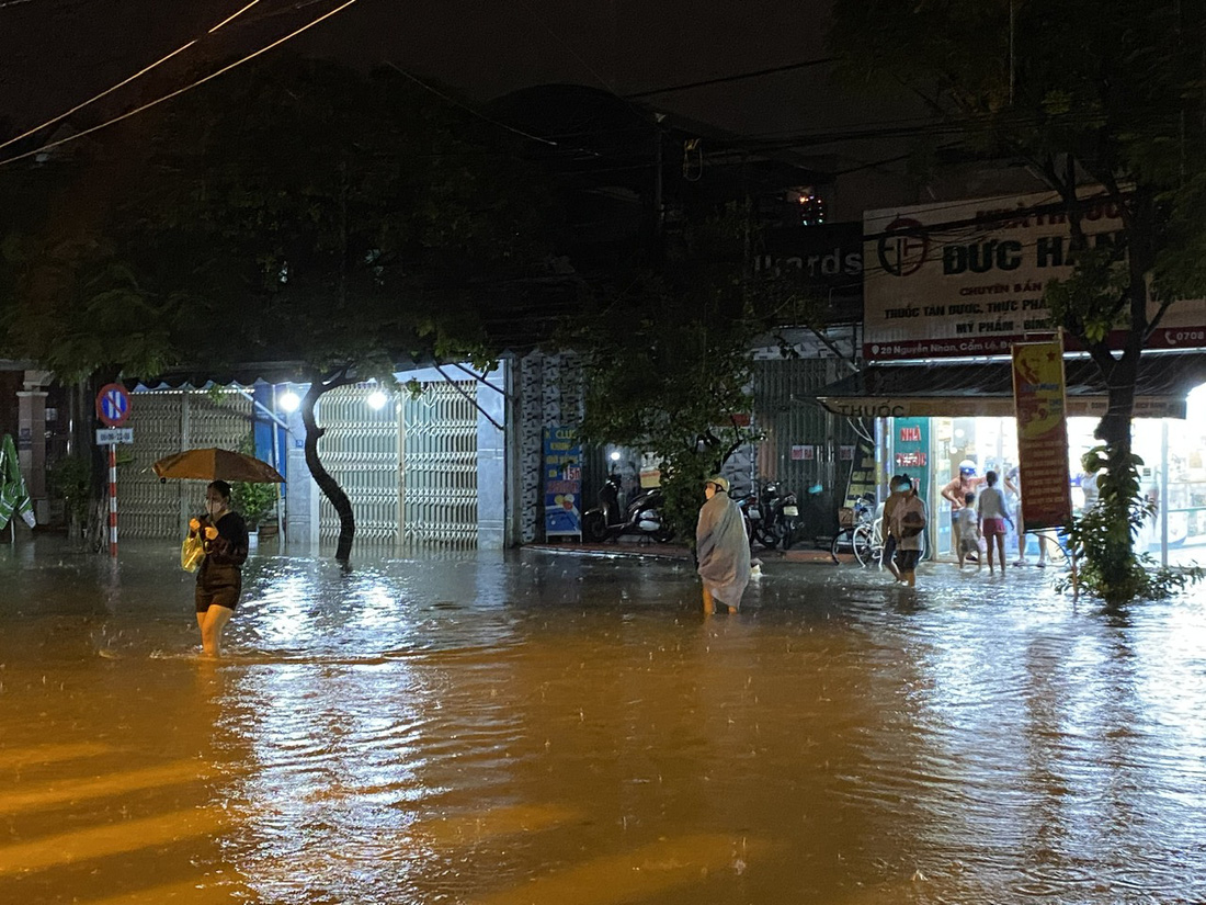 Tại tuyến đường Nguyễn Nhàn (quận Cẩm Lệ) dù tối 13-10 vẫn ngập khá sâu nhưng một số cửa hàng thiết yếu vẫn mở cửa do người dân đã chủ động chống ngập - Ảnh: TRƯỜNG TRUNG