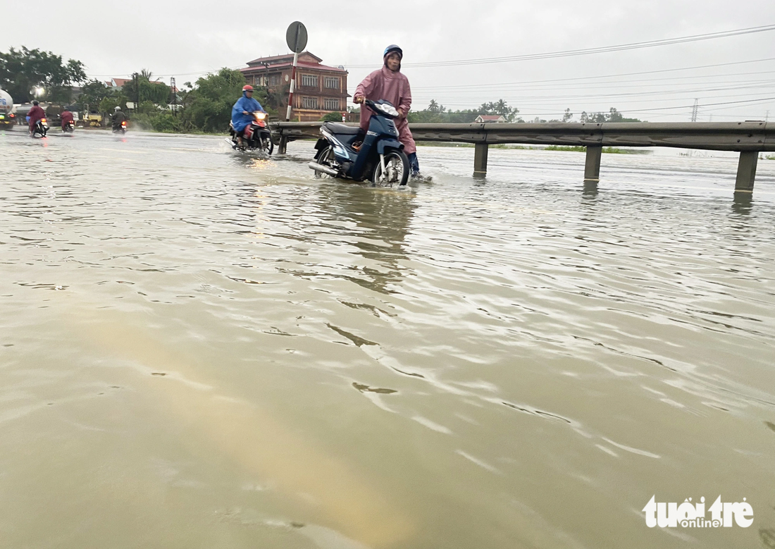 Người dân phải dắt xe máy qua đoạn ngập nước - Ảnh: LÊ TRUNG