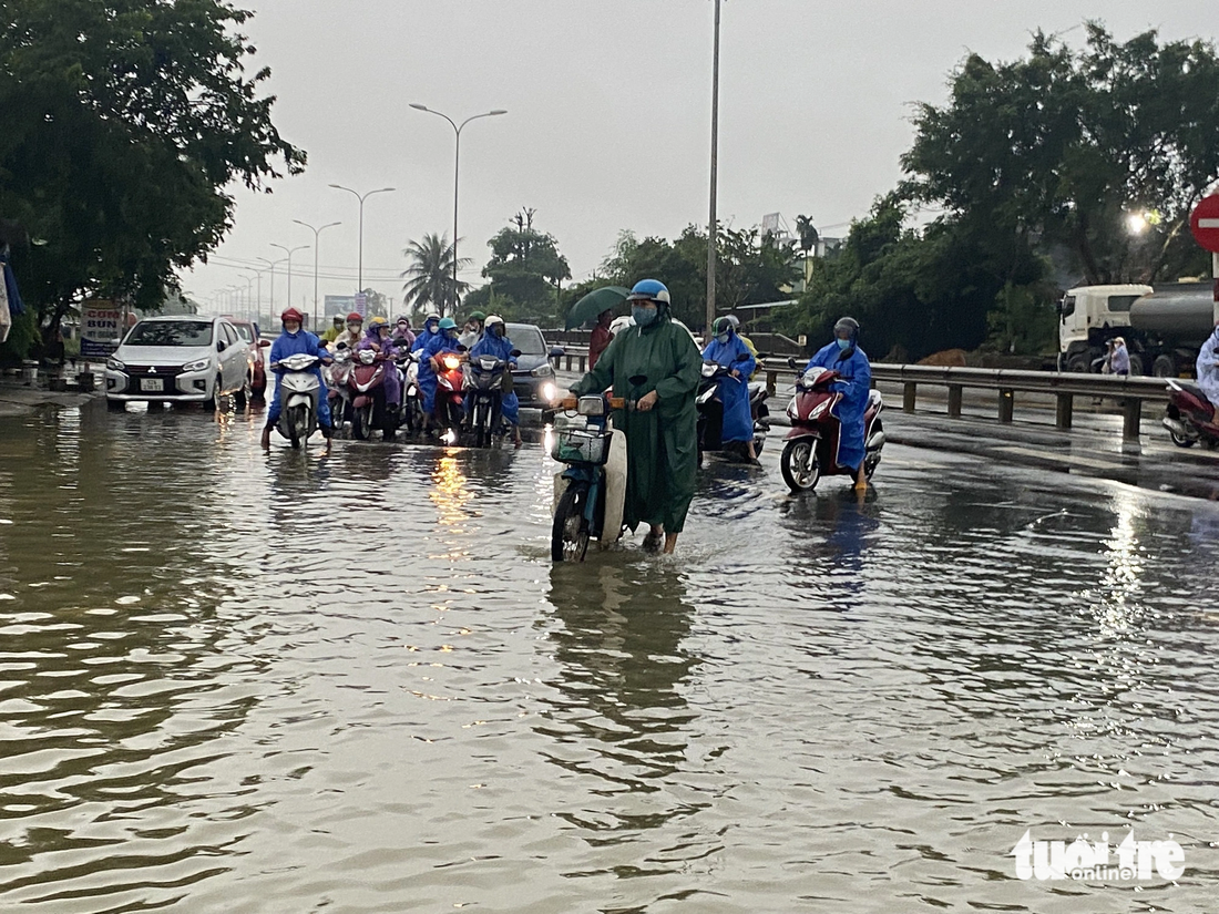 Một số công nhân ngần ngại đứng giữa đường không dám băng qua đoạn ngập - Ảnh: LÊ TRUNG