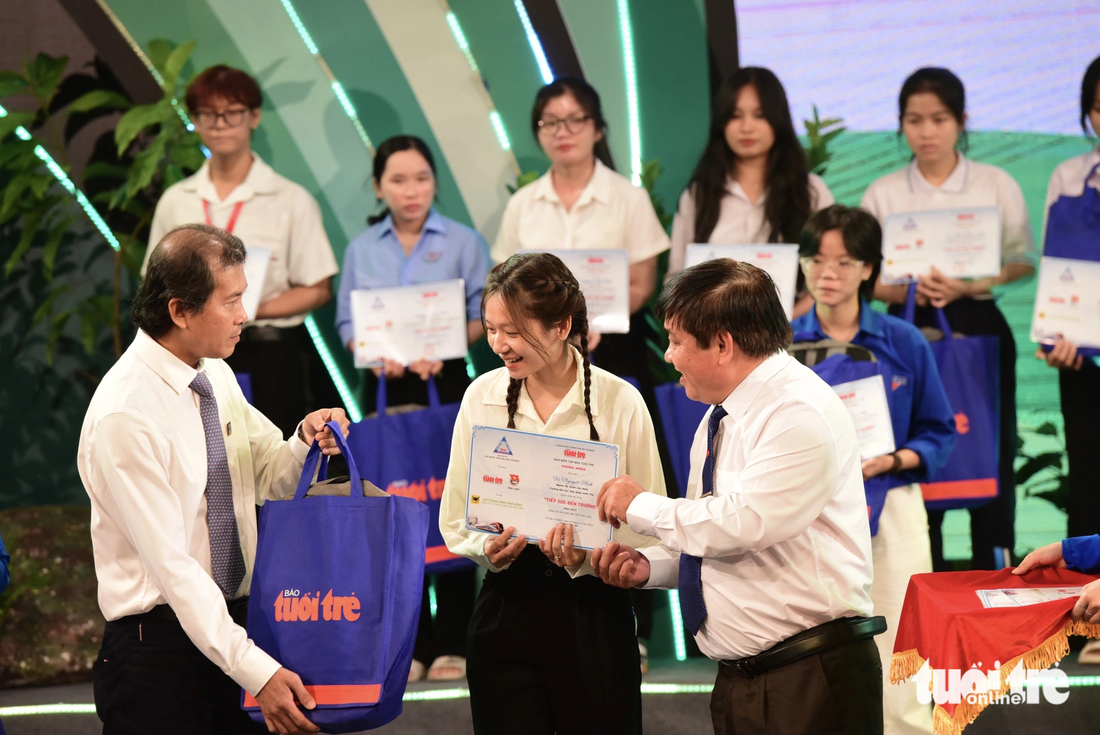 Ông Lê Thế Chữ, tổng biên tập báo Tuổi Trẻ (bên phải) cùng ông Phan Văn Tâm, phó tổng giám đốc Công ty cổ phần phân bón Bình Điền, trao học bổng cho tân sinh viên - Ảnh: DUYÊN PHAN