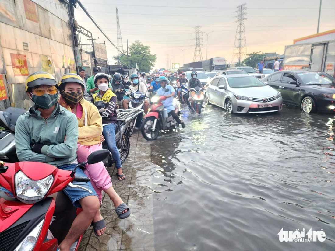 Nhiều xe máy phải tấp vào lề chờ bớt ngập và kẹt xe ở quận Bình Tân - Ảnh: NGỌC KHẢI