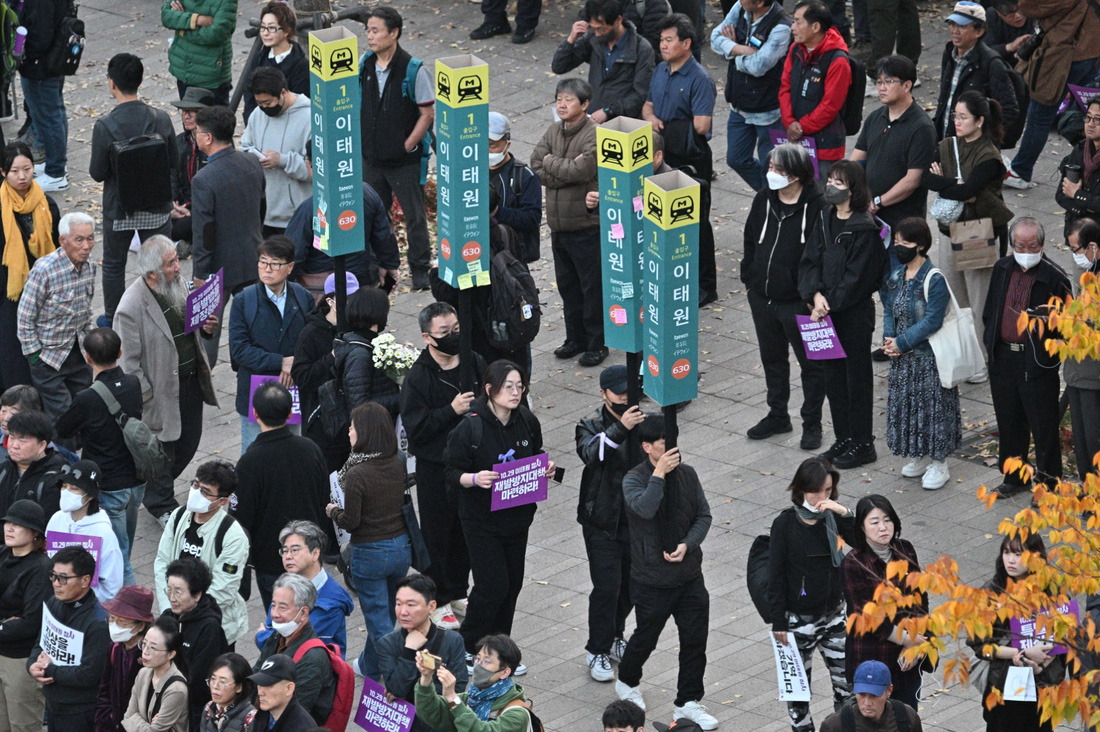 Người dân cầm mô hình biển báo ga tàu Itaewon tuần hành trong hoạt động tưởng niệm nạn nhân thảm kịch Itaewon - Ảnh: AFP