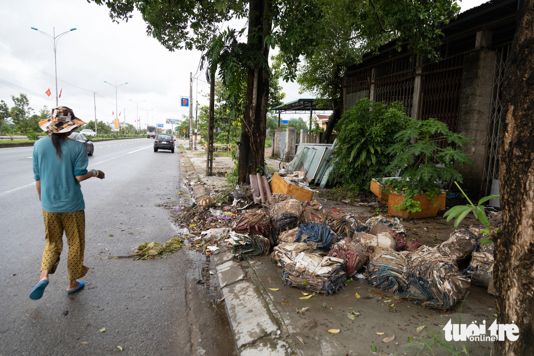 Vỉa hè quốc lộ 1A đoạn qua xã Triệu Ái (huyện Triệu Phong) chất đầy bao xi măng, rác thải nên người đi bộ phải đi xuống lòng đường - Ảnh: HOÀNG TÁO