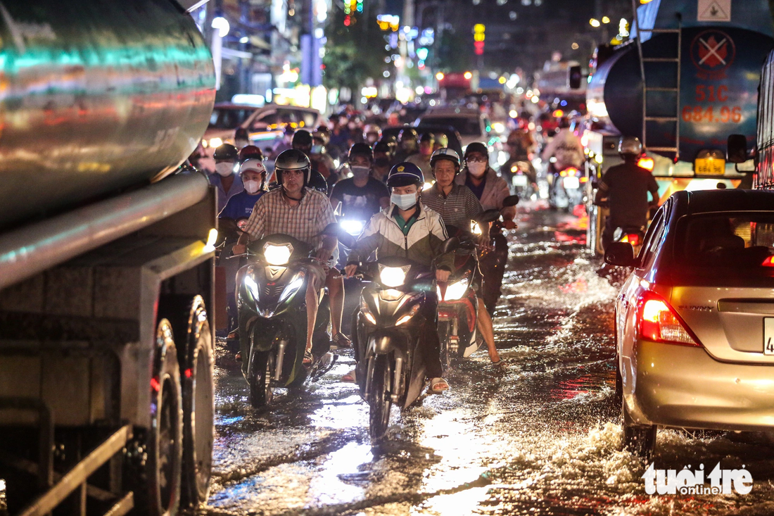 Lúc 19h, nhiều người đi xe máy phải men theo làn ô tô để vượt qua đoạn đường ngập trên đường Huỳnh Tấn Phát