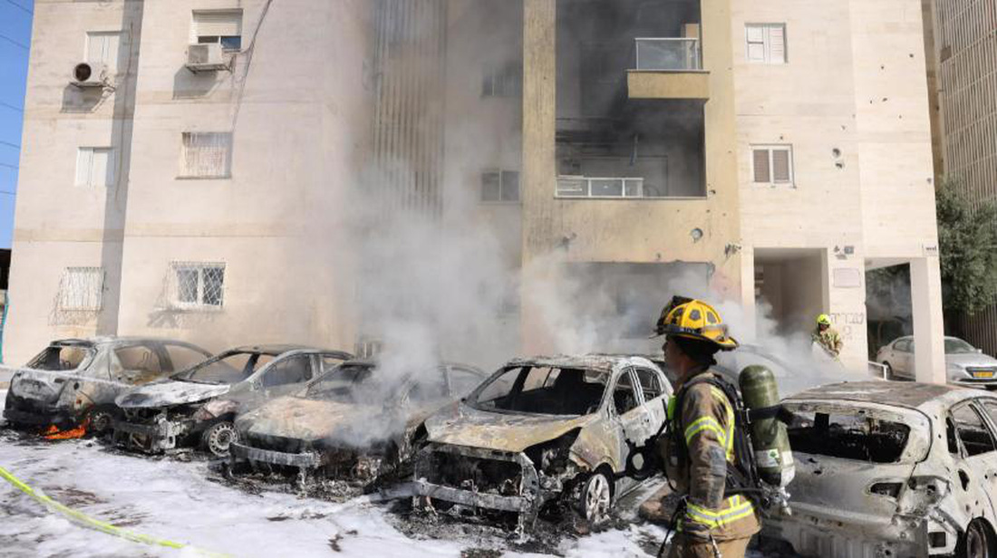 Đội cứu hỏa Israel dập tắt ngọn lửa ở bãi đậu xe bên ngoài một tòa nhà dân cư sau vụ tấn công thành phố Ashkelon, phía nam Israel ngày 7-10 - Ảnh AFP
