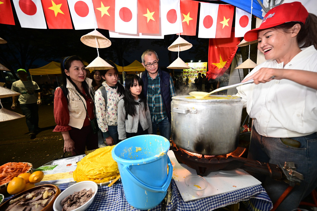 Gia đình chị Mỹ Hà (sống ở Tokyo) xem làm bánh phở tại gian hàng phở Hai Thiền ngày 7-10 tại Công viên Yoyogi - Ảnh: QUANG ĐỊNH