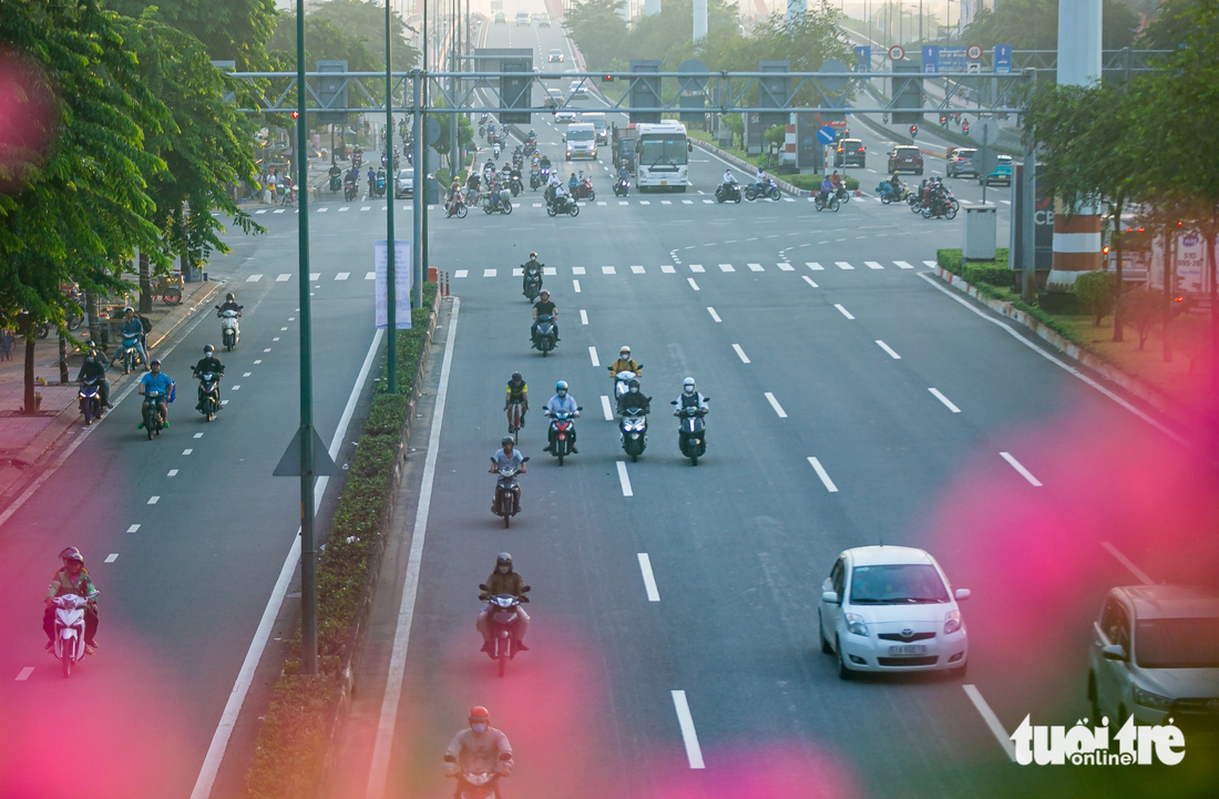 Một người đi xe đạp lọt thỏm giữa nhiều xe máy và ô tô trên đường Phạm Văn Đồng sáng 7-10