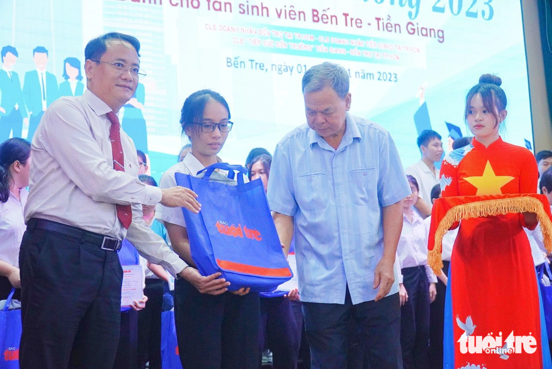 Ông Võ Thành Hạo - nguyên bí thư Tỉnh ủy Bến Tre và ông Nguyễn Hoàng Nguyên - phó tổng biên tập báo Tuổi Trẻ trao học bổng cho các tân sinh viên - Ảnh: MẬU TRƯỜNG