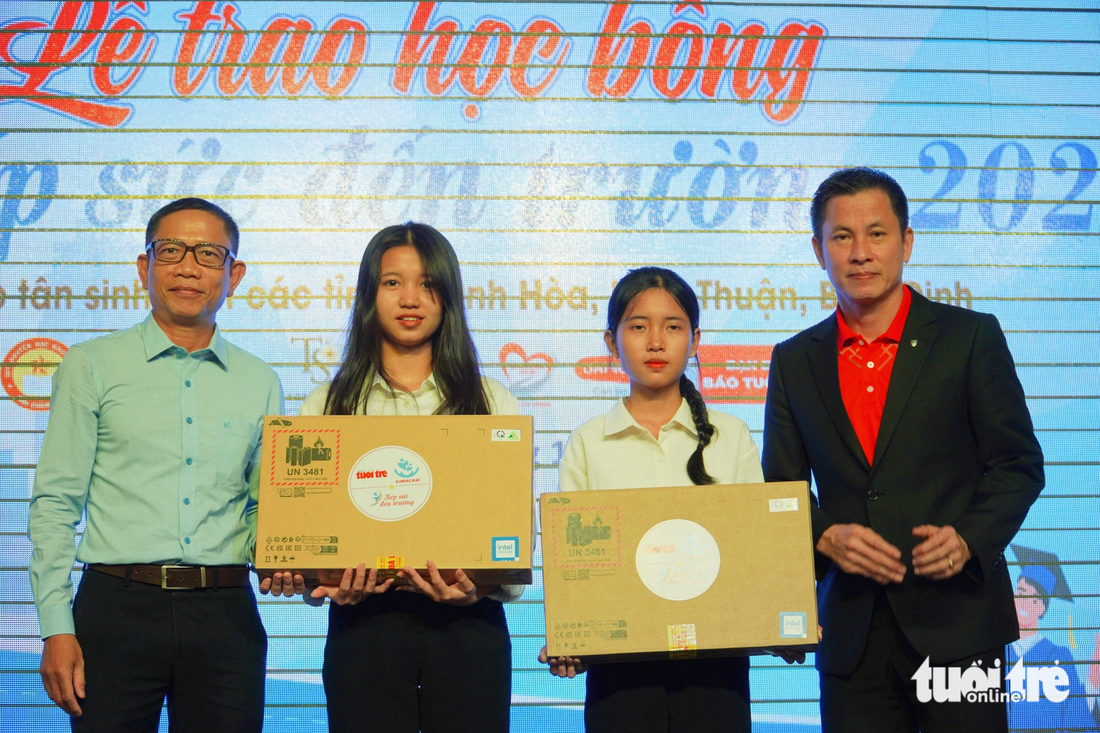 Hai tân sinh viên Lê Thảo Vi (thứ hai từ trái qua) và Lê Thị Kim Ngọc nhận laptop từ chương trình - Ảnh: TRẦN HOÀI