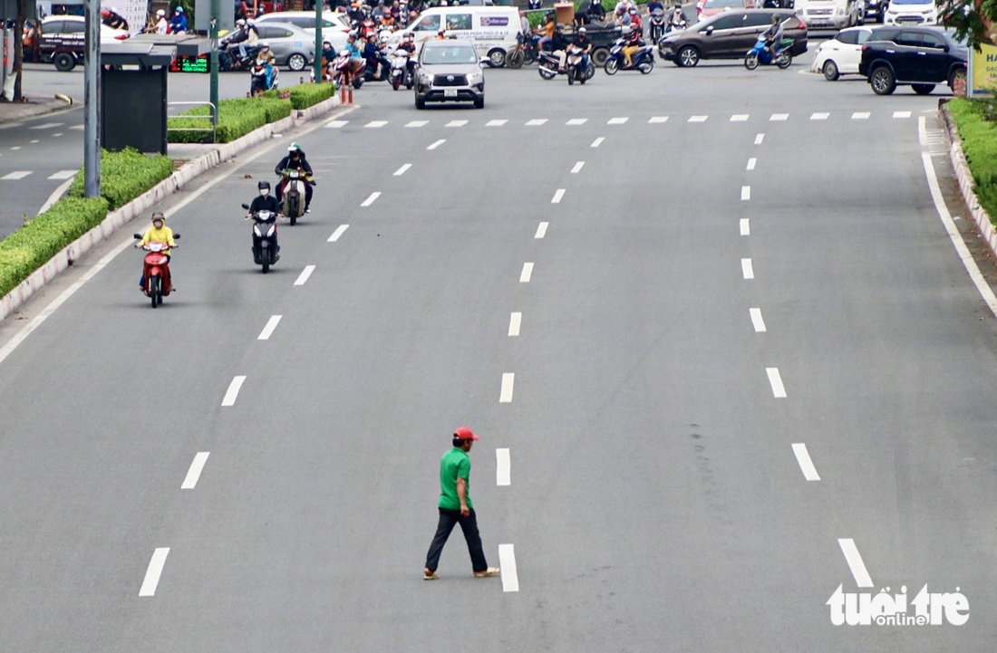 Không chỉ xe máy, nhiều người đi xe đạp, đi bộ cũng ngang nhiên đi tắt băng ngang qua đường bất chấp xe ô tô chạy - Ảnh: TIẾN QUỐC