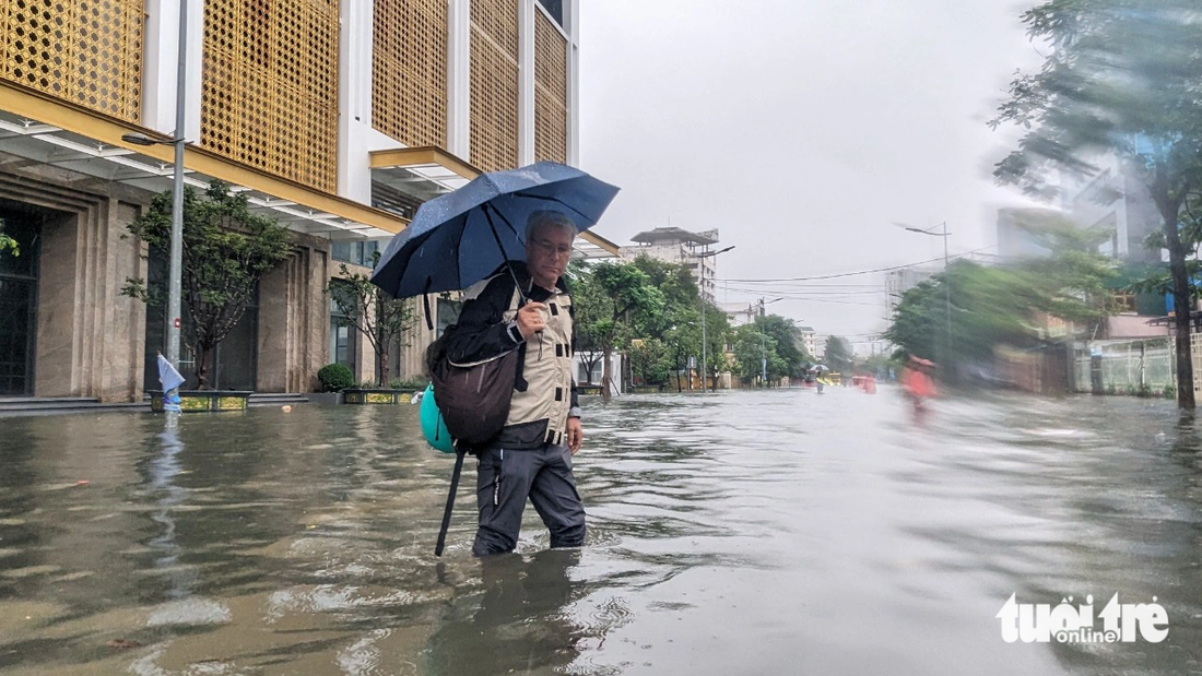 Một du khách nước ngoài lội nước lụt trên đường