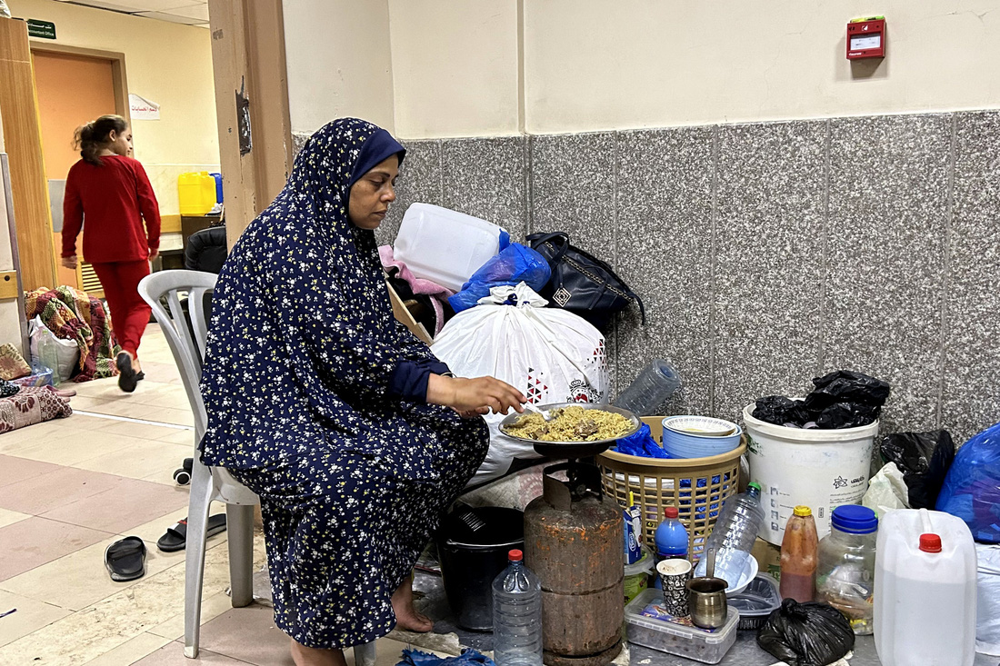 Một phụ nữ mất nhà cửa nấu ăn trong khuôn viên Bệnh viện Al Shifa hôm 10-11. Trong cuộc đột kích ngày 15-11, IDF không cho phép người dân trú tại đây rời bệnh viện, song cũng chưa nổ phát súng nào trong khuôn viên cơ sở y tế này - Ảnh: AFP