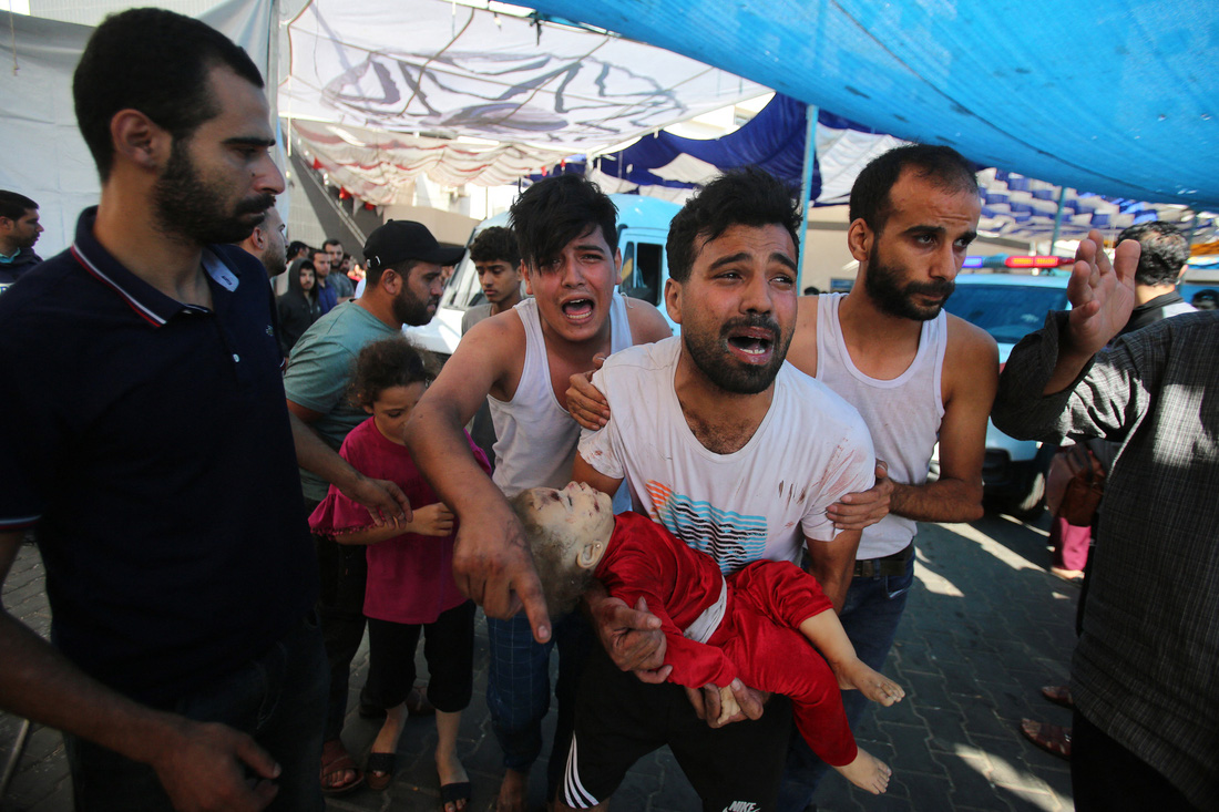 Người đàn ông bế một trẻ nhỏ bị thương do không kích của Israel hôm 4-11 chạy đến Bệnh viện Al Shifa cấp cứu. Đây là một trong những địa điểm chính tiếp nhận điều trị các nạn nhân từ những cuộc tấn công của Israel - Ảnh: AFP