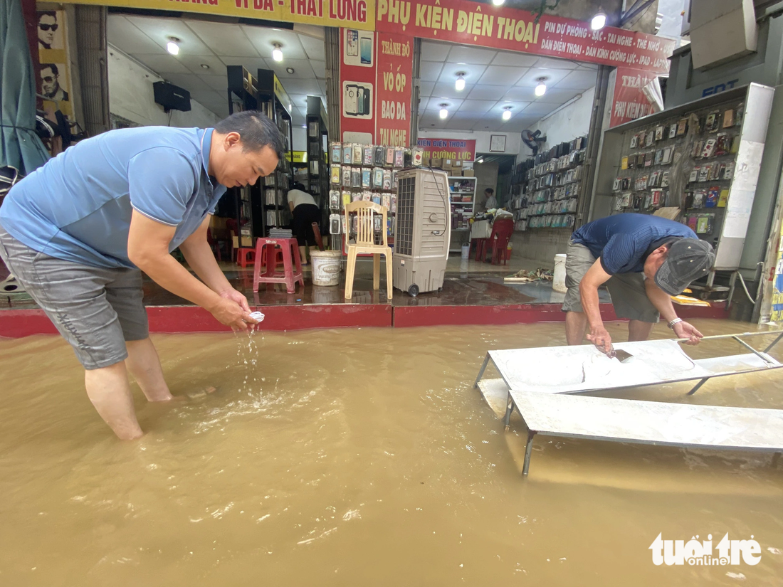 Nước lũ rút ra, người dân dọn dẹp vệ sinh cửa hàng - Ảnh: LÊ TRUNG