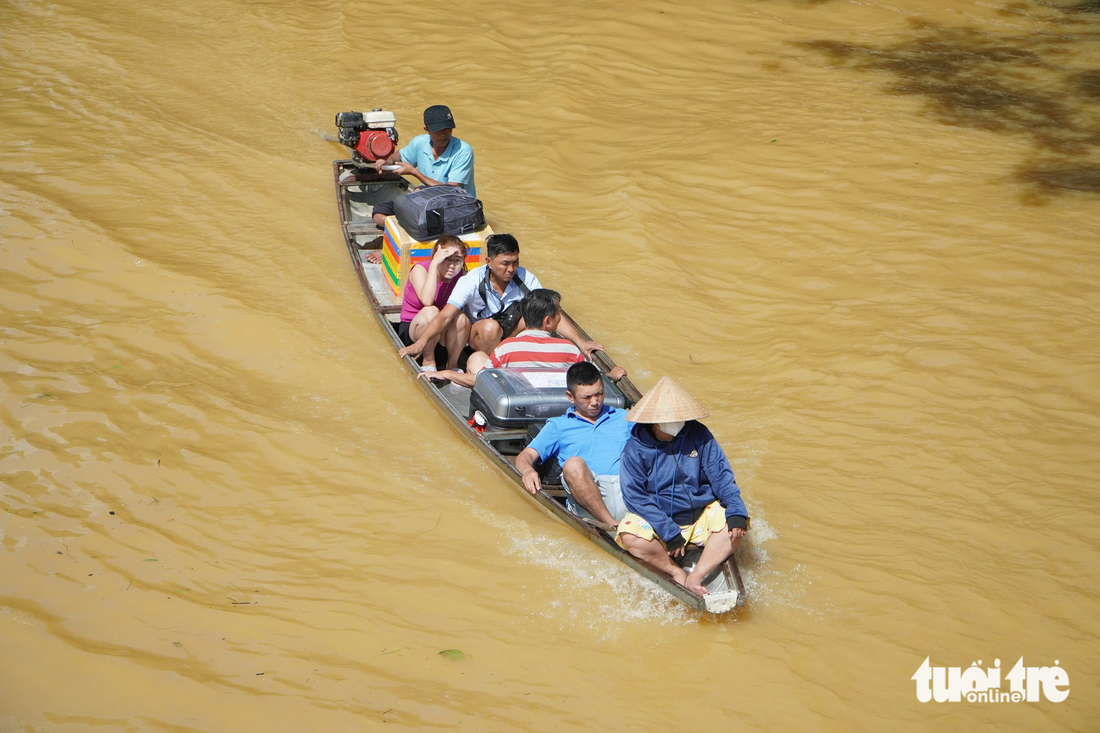 Người dân di chuyển bằng thuyền trong dòng nước lũ - Ảnh: LÊ TRUNG