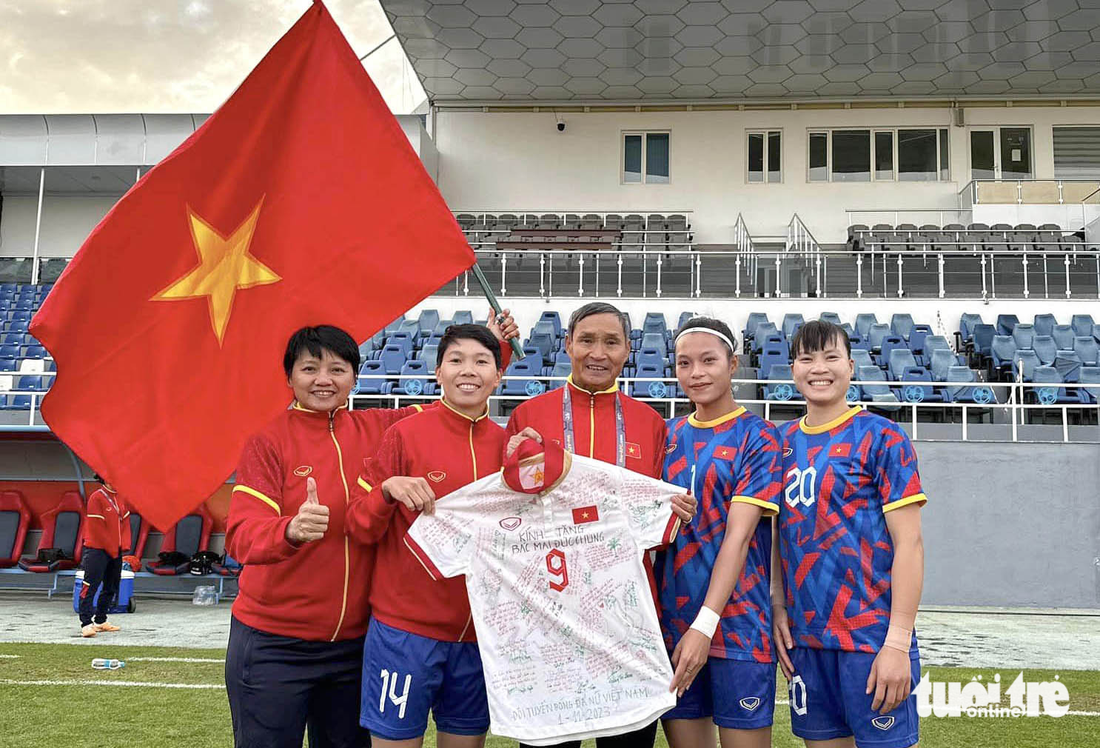 HLV Mai Đức Chung hạnh phúc bên chiếc áo của đội trưởng Huỳnh Như có ghi cảm xúc của các học trò khi chia tay - Ảnh: FBNV