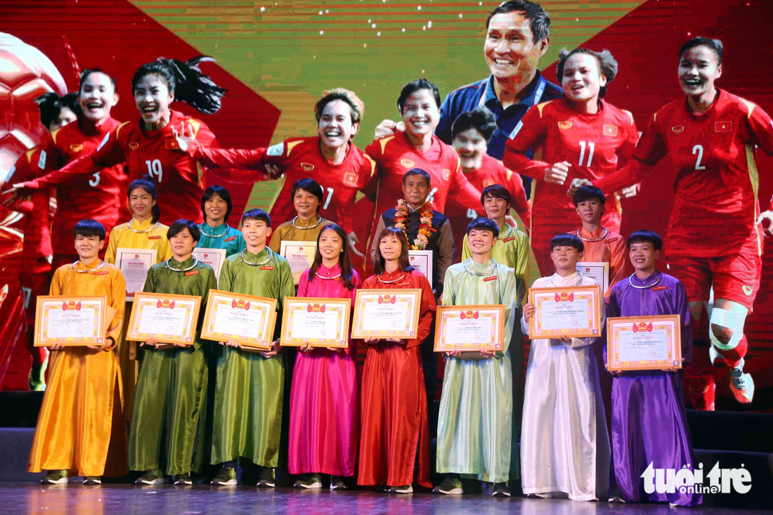 HLV Mai Đức Chung cùng các cầu thủ nữ Việt Nam mặc áo dài được tặng trong chương trình giao lưu với bạn đọc Tuổi Trẻ sau khi giành vé dự World Cup - Ảnh: N.K.