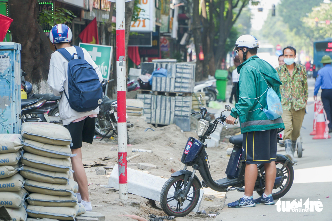 Em học sinh gặp khó khi dắt xe vào cửa hàng văn phòng phẩm để mua đồ dùng học tập - Ảnh: PHẠM TUẤN