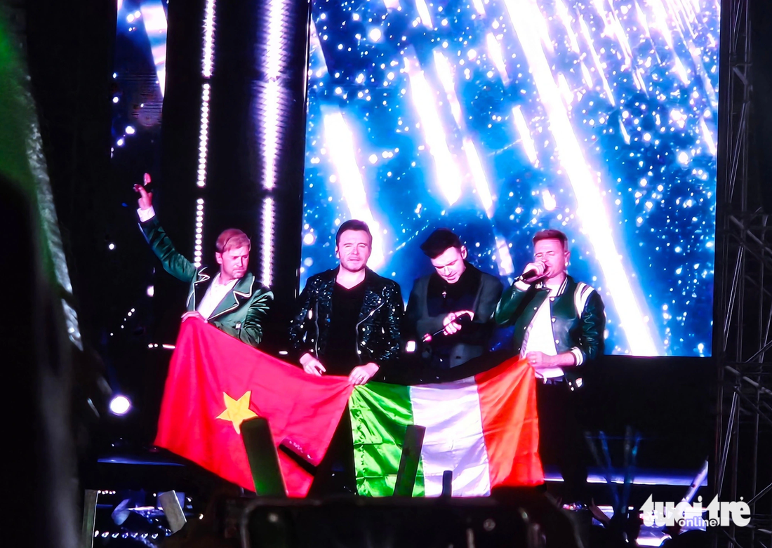 Nhóm nhạc Westlife cầm cờ Việt Nam và Ireland trong phần kết chào khán giả, tối 21-11 - Ảnh: MI LY