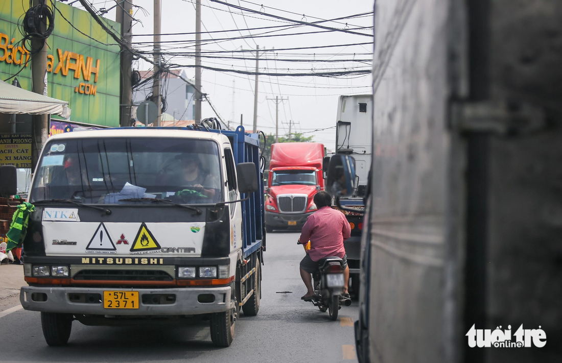 Đường Nguyễn Duy Trinh là đường độc đạo dẫn vào cảng Phú Hữu nên xe tải cỡ lớn và xe container chiếm số nhiều. Xe máy hầu như phải luồn lách để đi lại - Ảnh: LÊ PHAN