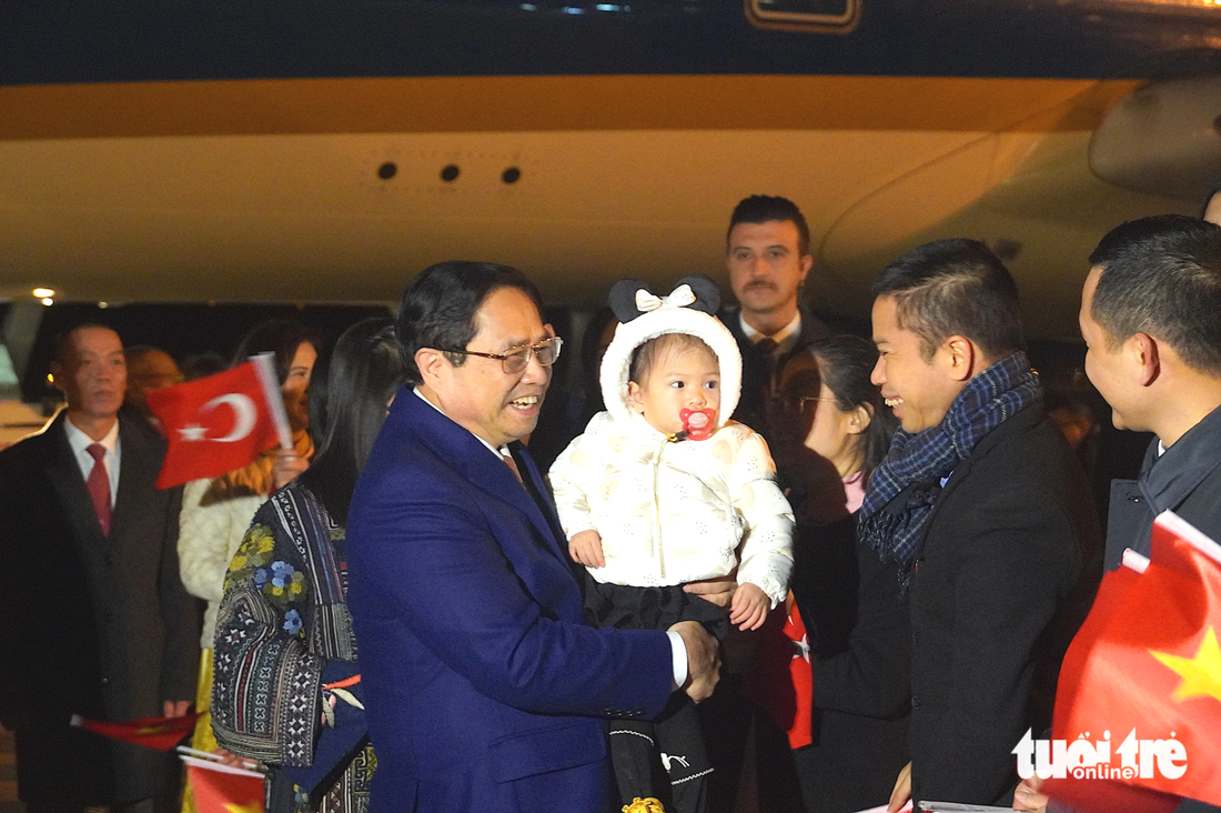 Thủ tướng bế một cháu nhỏ tại sân bay trong sự chào đón nồng nhiệt của kiều bào - Ảnh: NGỌC AN