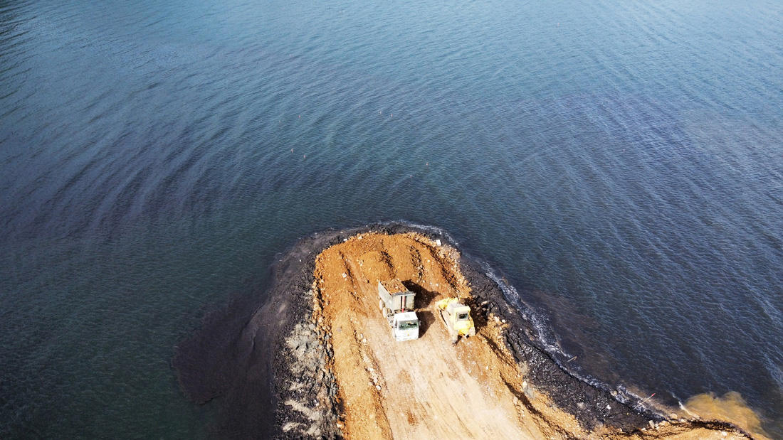 Nước tại vùng vịnh chuyển màu khi hoạt động đổ đất đá tạo lối đi của dự án được triển khai - Ảnh: L.DŨNG