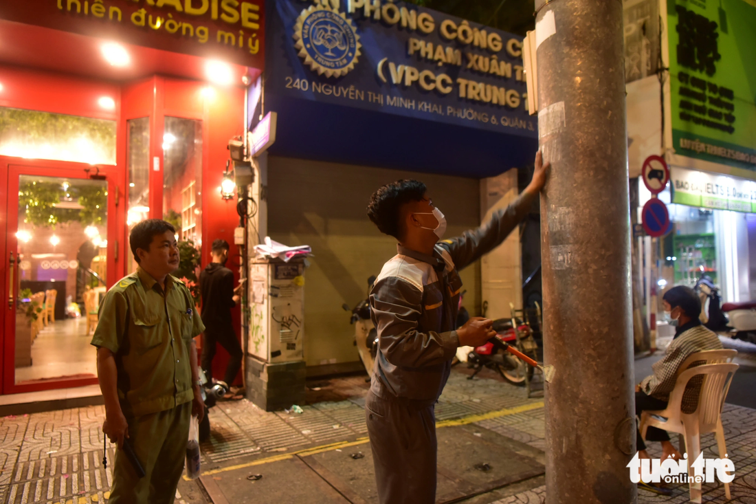 Những người dán quảng cáo trái phép bị công an phường Võ Thị Sáu (quận 3) phạt cạo sạch quảng cáo trên đường Nguyễn Thị Minh Khai 