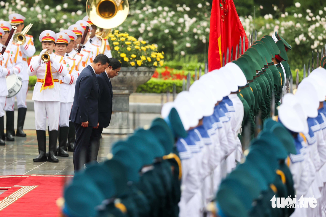 Hai Thủ tướng cúi đầu chào quân kỳ Quân đội nhân dân Việt Nam trước khi duyệt đội danh dự - Ảnh: NGUYỄN KHÁNH