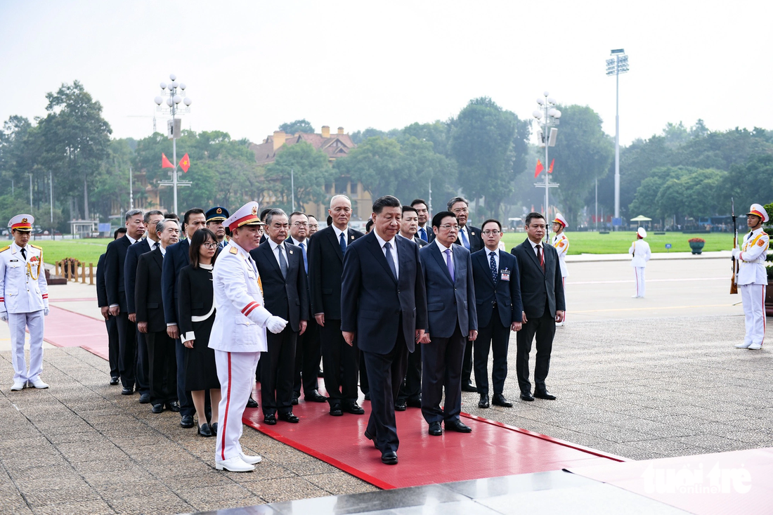 Tổng bí thư, Chủ tịch nước Trung Quốc Tập Cận Bình tiến về phía trước để chỉnh dòng chữ trên vòng hoa - Ảnh: NAM TRẦN