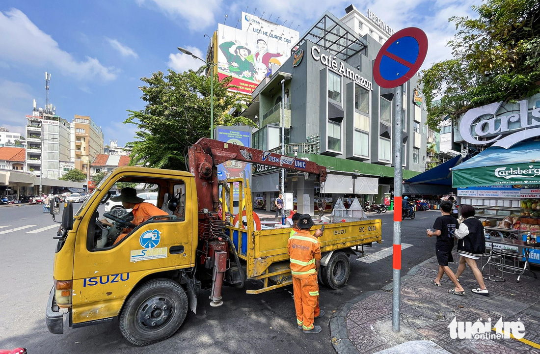Các công nhân cầu đường lắp đặt, chỉnh sửa biển báo giao thông ở đầu đường Lưu Văn Lang - Ảnh: LÊ PHAN