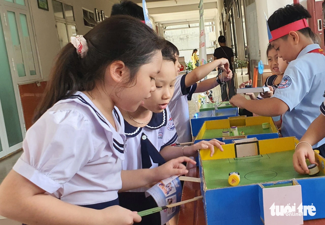 Nhóm nữ sinh Trường tiểu học Lê Thị Hồng Gấm tỏ ra rất ngạc nhiên khi khám phá nguyên lý của trò chơi bóng đá nam châm - Ảnh: HOÀNG HƯƠNG