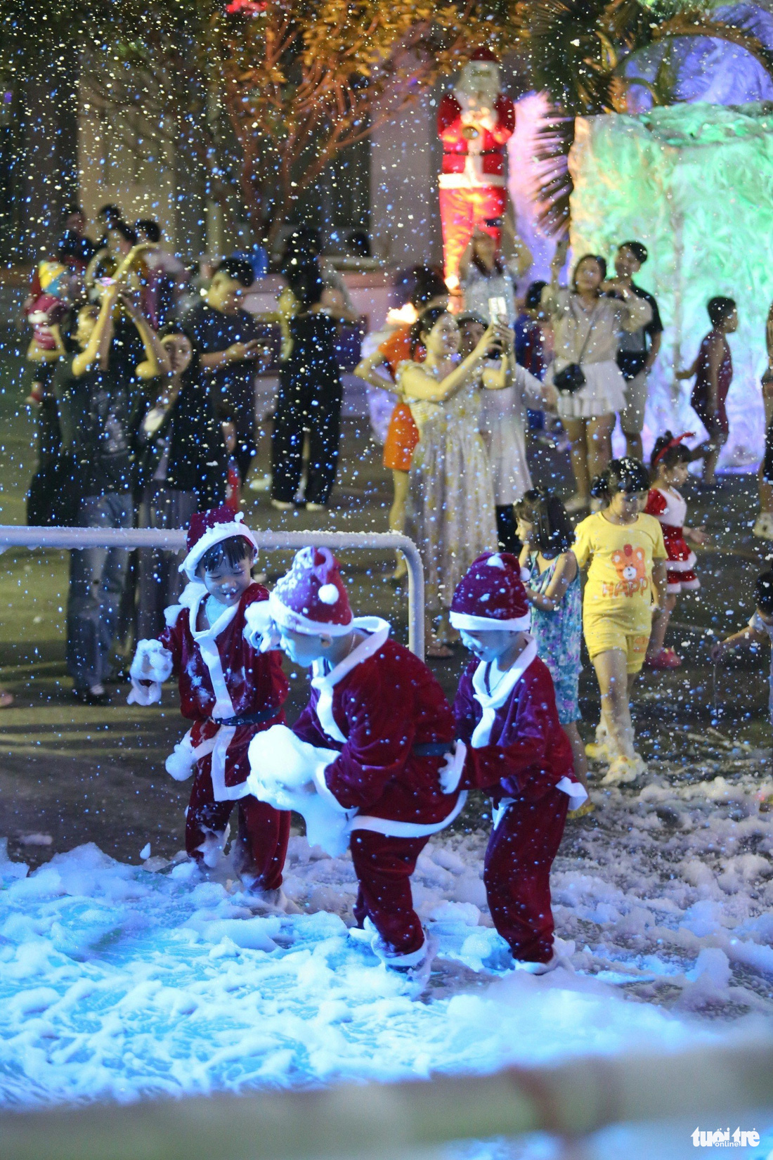 Mô hình hang đá với hai máy phun tuyết tự động ở nhà thờ Bình An Thượng (quận 8) thu hút hàng trăm người tới tham quan. Nhiều em bé thích thú được nô đùa, chạy nhảy dưới tuyết - Ảnh: PHƯƠNG QUYÊN